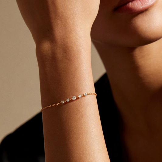 Gold gradient moissanite station bracelet worn on wrist, minimalist central stone jewelry for women