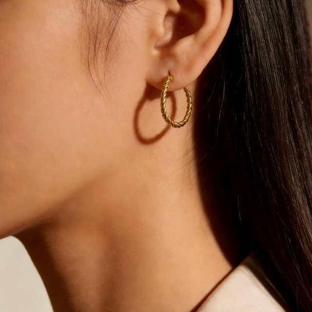 Gold twisted small hoop earrings worn on ear, minimalist everyday jewelry for women