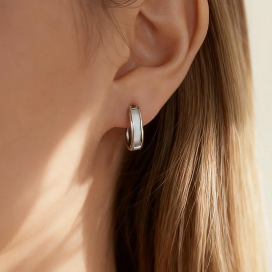 Silver brushed huggie hoop earring worn on ear, minimalist matte finish jewelry for women