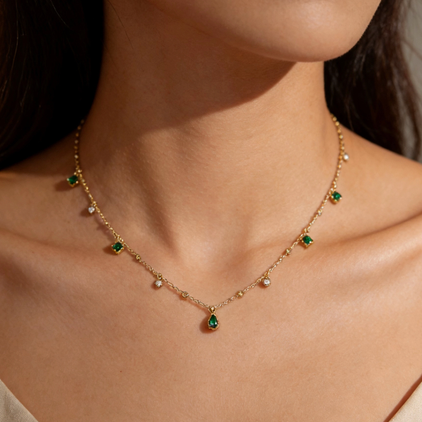 Gold emerald gemstone teardrop station necklace worn on neck, minimalist square emerald and crystal charm jewelry for women