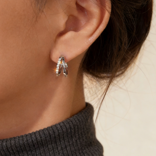 Silver double hoop crossover cubic zirconia hoop earrings worn on ear, minimalist dainty cz layering jewelry for women
