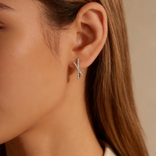 Silver moissanite criss-cross stud earrings worn on ear, minimalist moissanite X-design stud jewelry for women